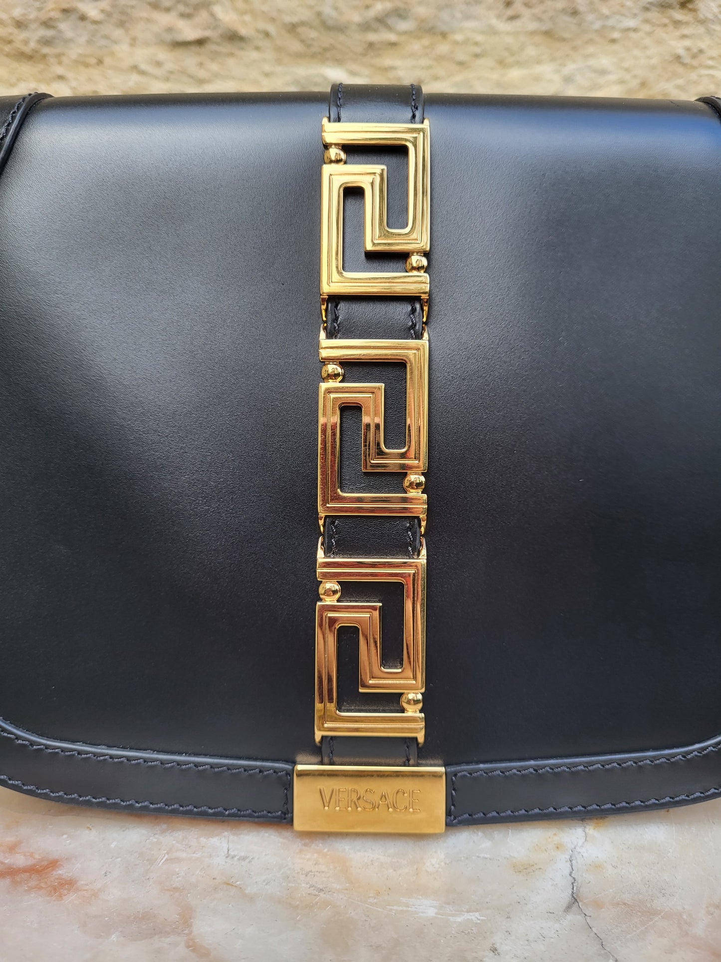 Versace Greca Goddess black leather crossbody bag, brand new with tags. Close up of Versace logo.